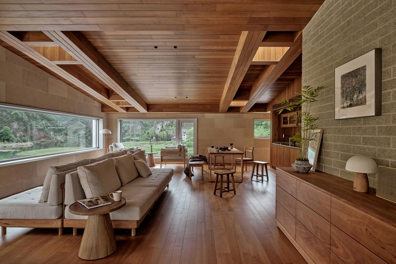 Living room with exposed timber beams and wide horizontal windows framing views of the garden beyond