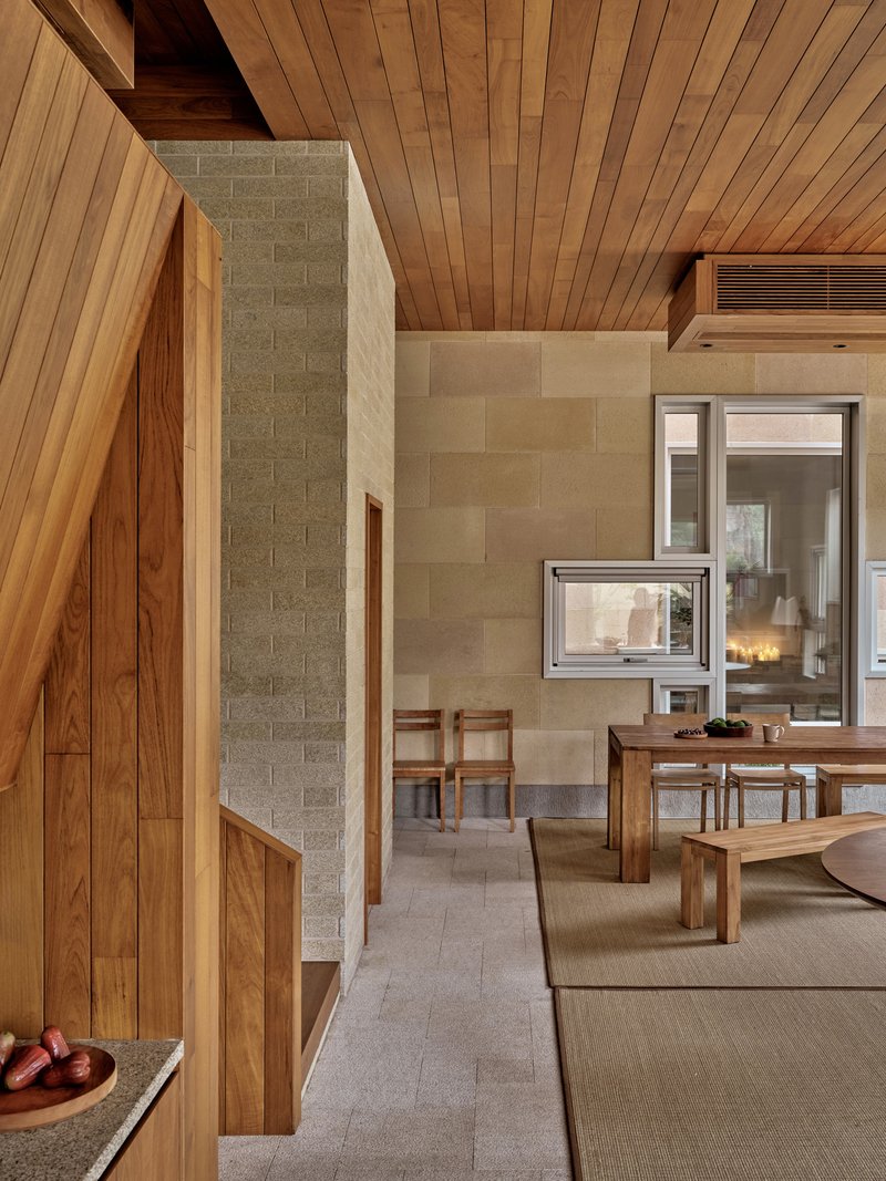 Living area with timber ceiling, concrete block walls and a double-sided fireplace connecting to the dining space