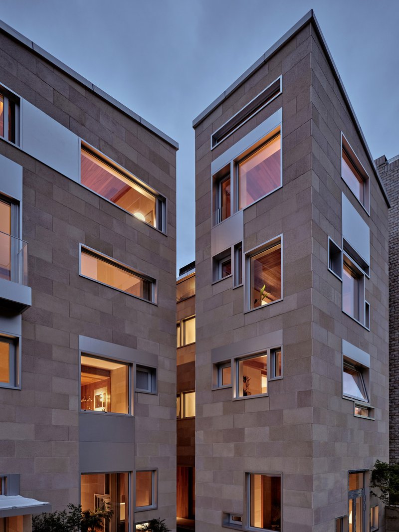 Interlocking concrete block facades with rectangular window openings illuminated at dusk