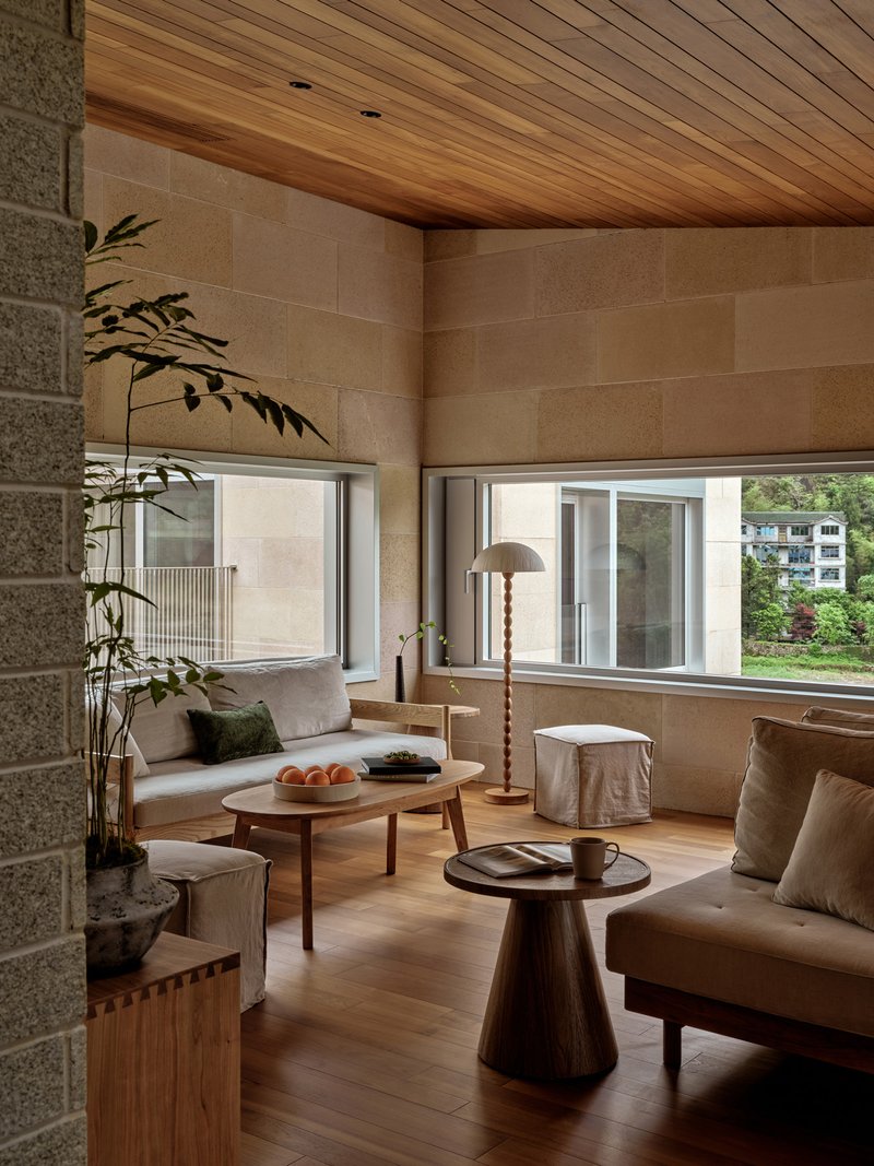 Living room with horizontal stone block walls and timber ceiling beside a potted bamboo plant