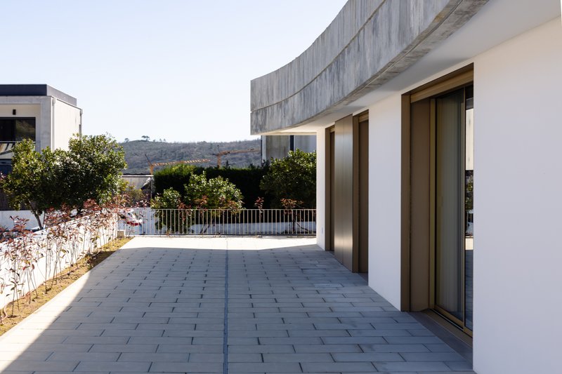 Paved terrace with planted bed and curved concrete wall backing onto hillside landscape