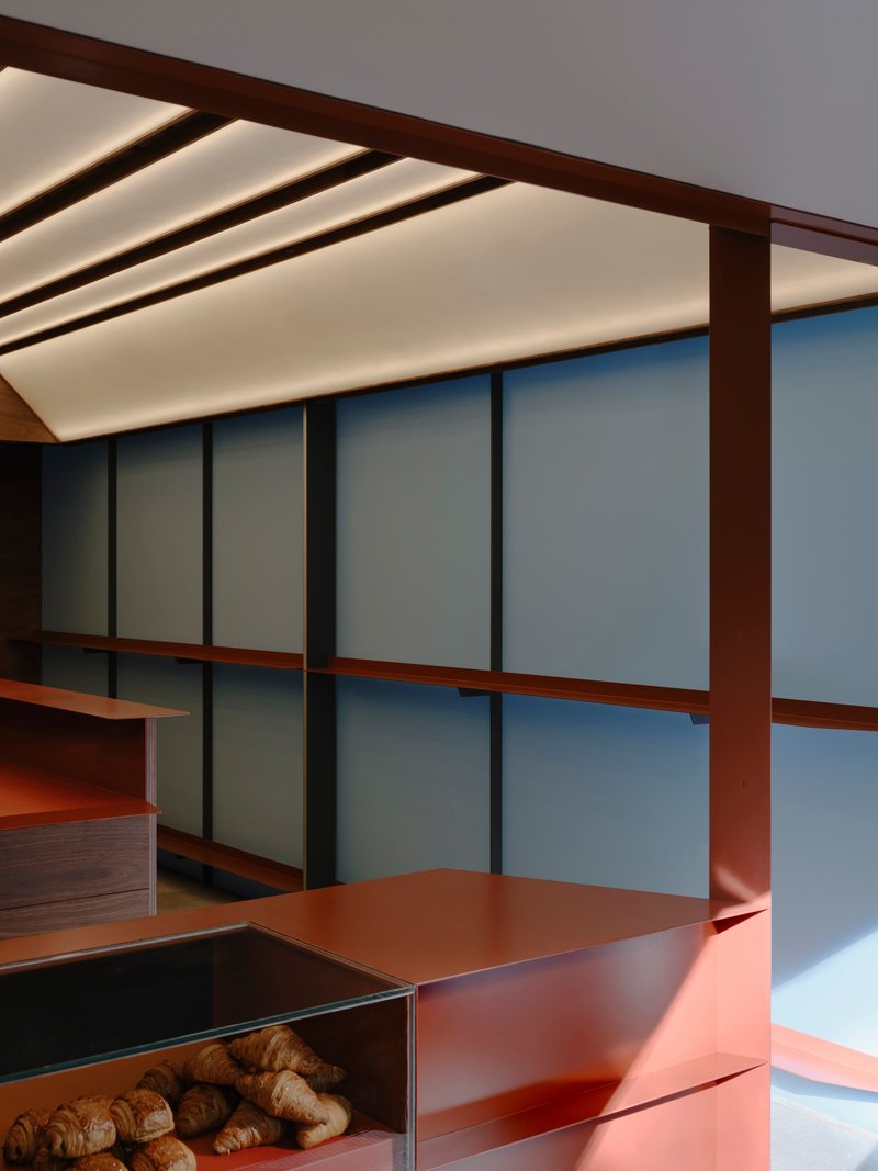 Backlit ceiling baffles above a copper counter and translucent glass panel wall with timber mullions