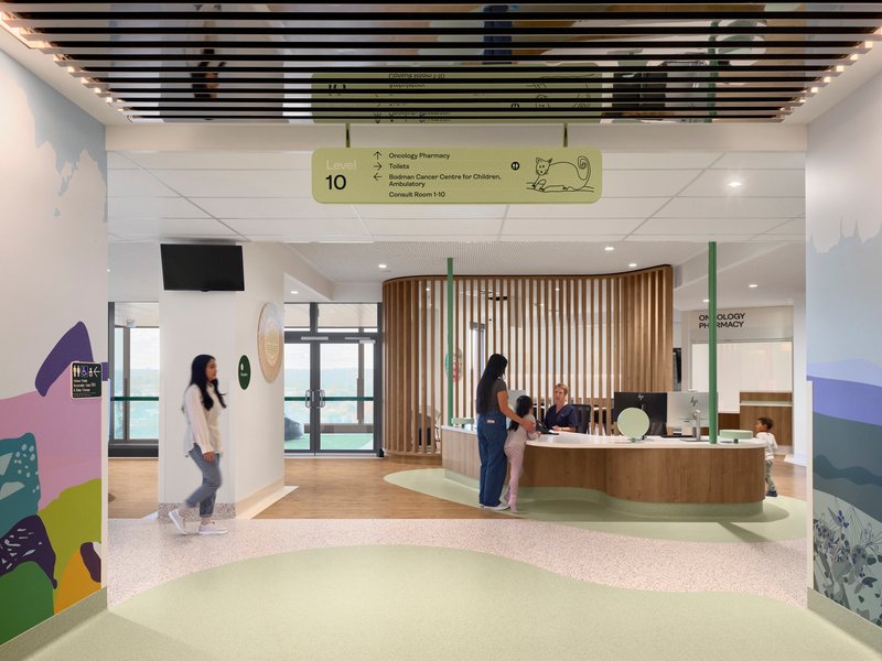 Reception area with curved timber slat screen and terrazzo flooring with visitors at the desk