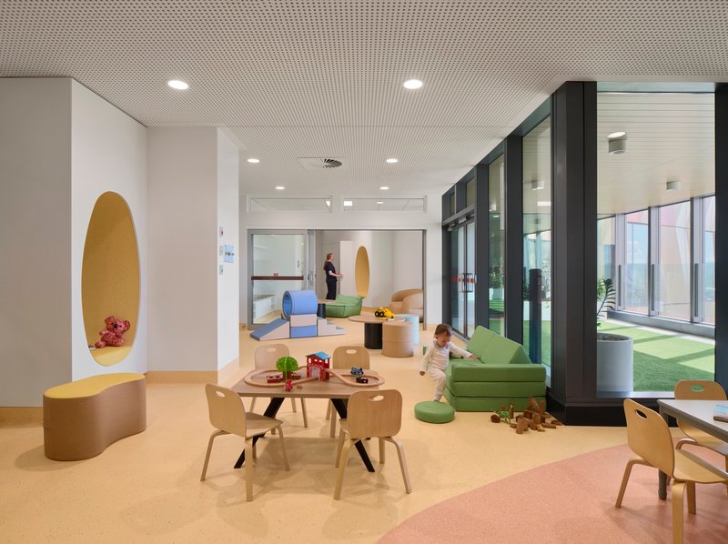 Play area with timber furniture, oval wall alcove, and glazed courtyard doors with a child on the floor