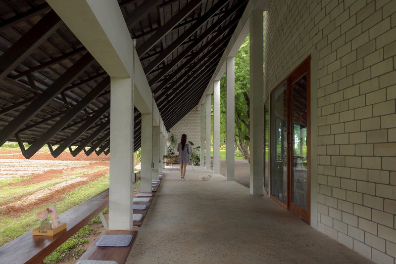 Covered walkway with white columns and diagonal timber roof structure as a person walks through