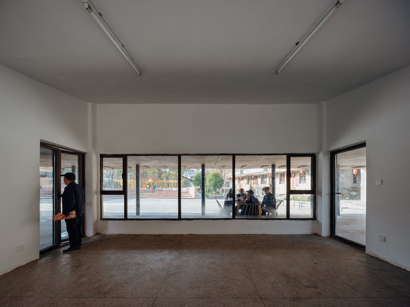 White interior room with continuous horizontal window opening overlooking the street and a person by the door