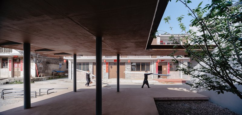 View through the pavilion's timber-lined ceiling toward surrounding residential buildings with pedestrians crossing the plaza