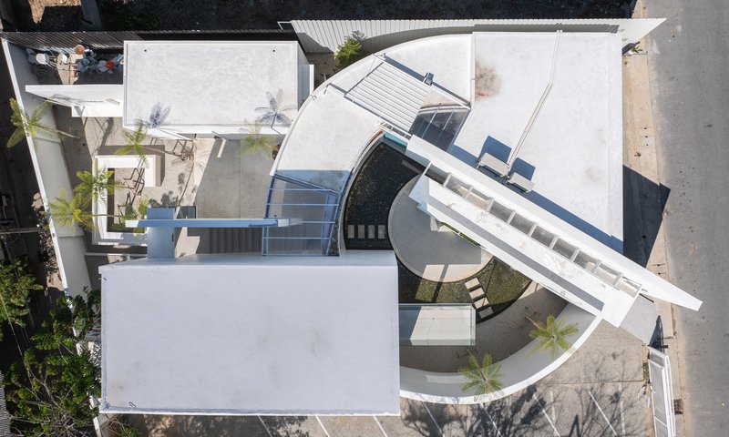 Aerial view of white rooftop with curved canopy, pool and louvered shading elements in bright sunlight