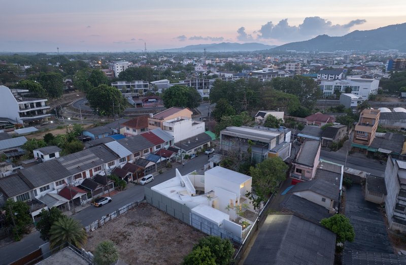 Aerial view of the white angular volumes set within a dense residential neighborhood at dusk