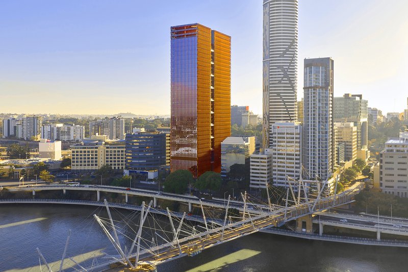 Aerial view of two high-rise towers with vertical bronze louvres beside a pedestrian bridge at dusk