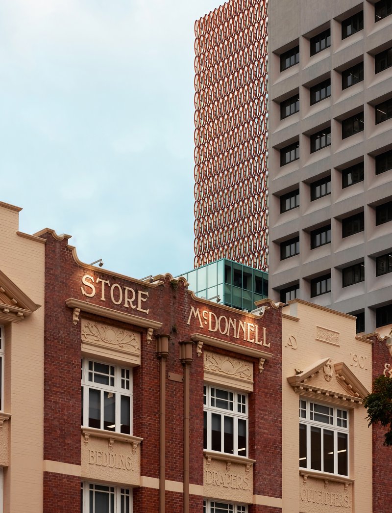 Ornamental brick facade of a heritage building at street level with tall residential towers rising behind