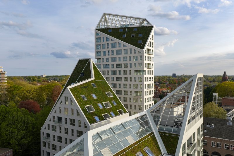 Aerial view of the clustered towers with planted and glazed gable roofs under partly cloudy skies