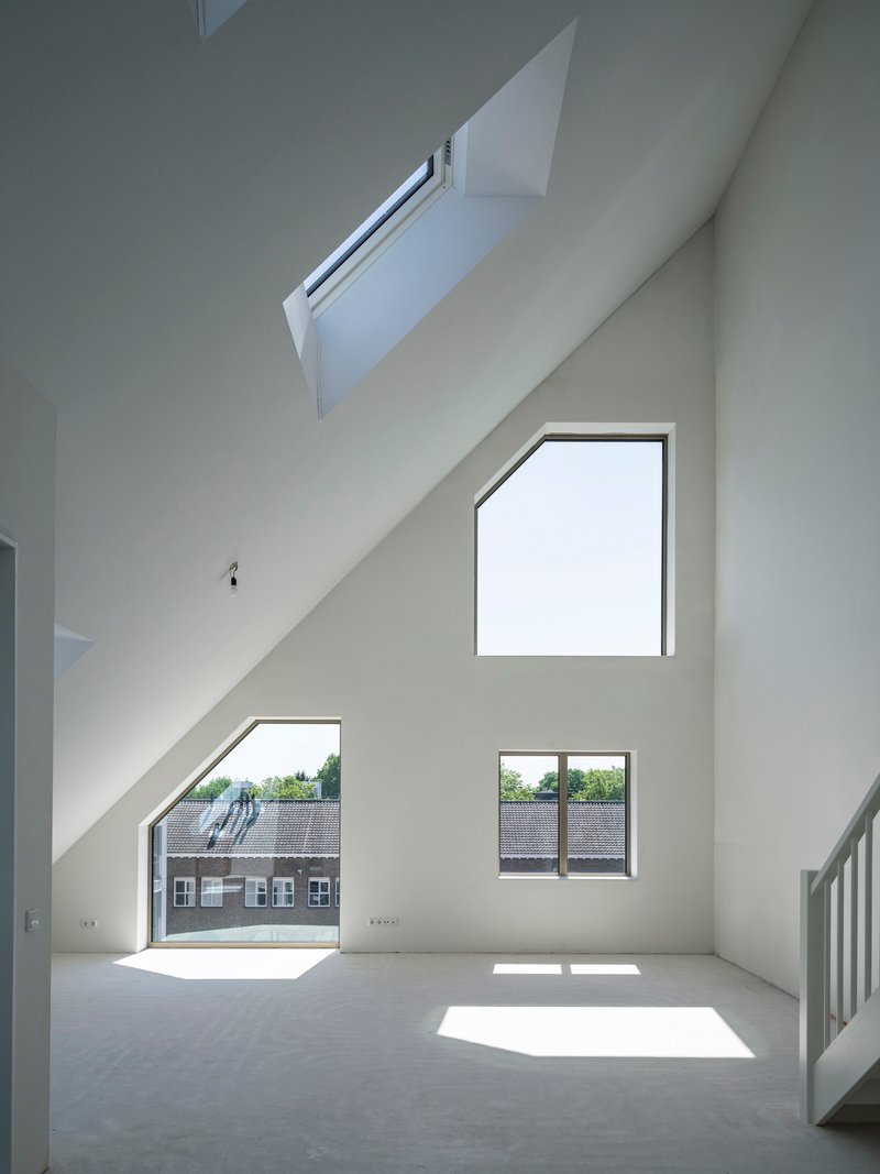 Double-height interior space with slanted walls and scattered pentagonal windows casting sunlight across the floor