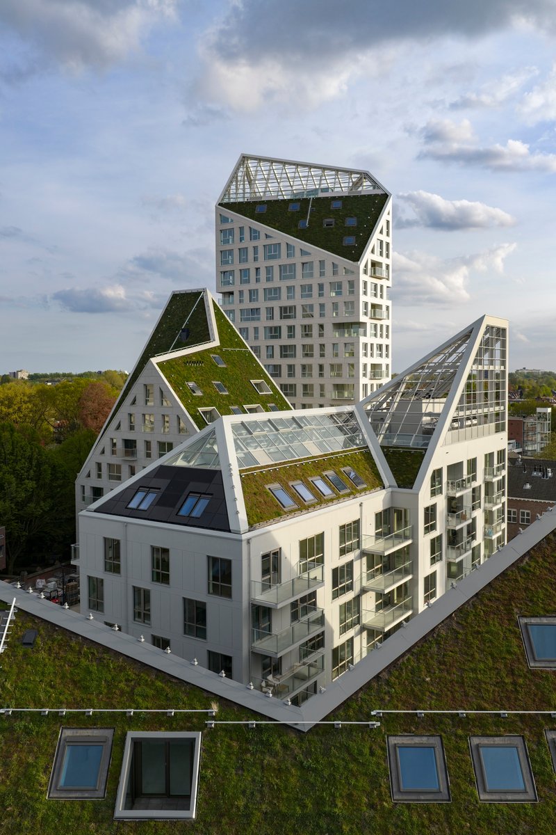 Aerial view of stacked green roofs and glazed gables above terraced residential volumes