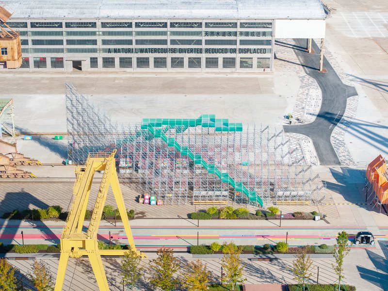 Aerial view showing the triangular metal framework with colored infill panels on the waterfront plaza
