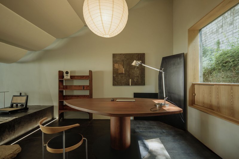 Office space with round timber table and paper lantern beside a glass brick window