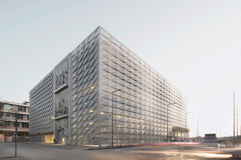 Corner view of the triangulated metal facade with perforated panels under an overcast sky