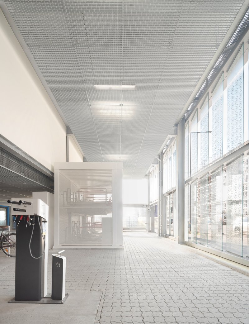 Interior ground floor corridor with perforated metal ceiling and full-height glazed curtain wall
