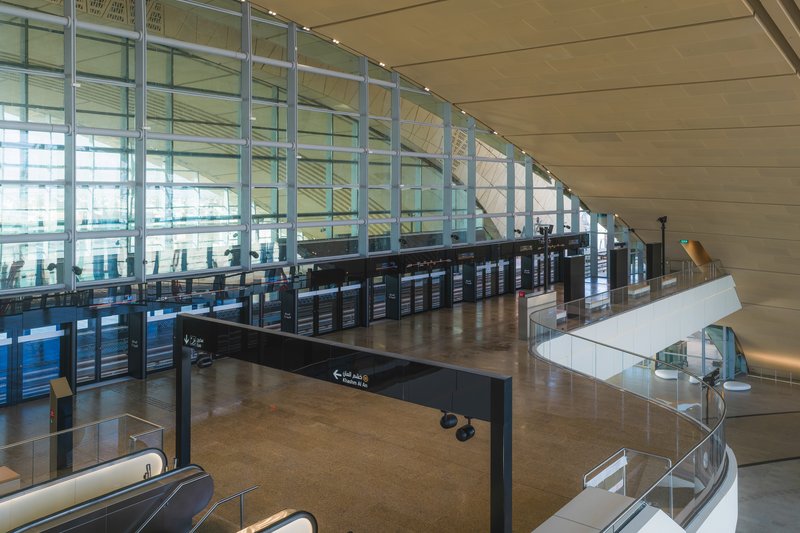 Interior concourse with curved ceiling, glass curtain wall, and spiral staircase descending to lower level
