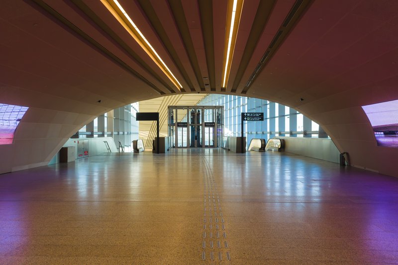 Arched corridor with radiating timber beams illuminated by integrated ceiling strips at dusk