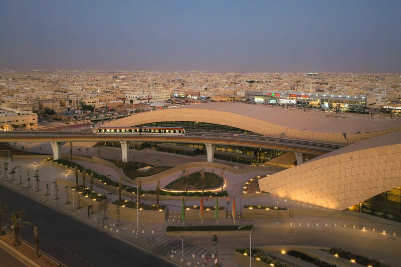 Aerial view of the curved roof spanning over highway infrastructure and planted courtyards at twilight