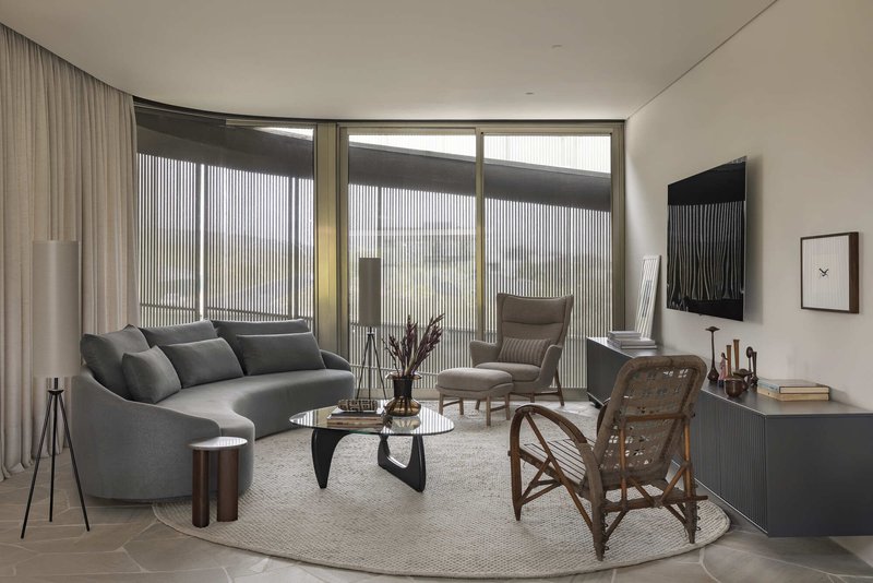 Living room with curved sofa and floor-to-ceiling windows framed by vertical metal screens