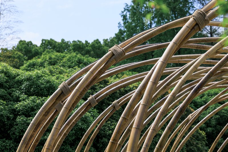 Close-up of wrapped bamboo joints where bundled poles converge in sweeping arched structure