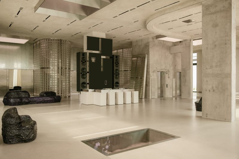 Lobby space with exposed concrete columns, curved ceiling cutout and recessed floor opening with glass