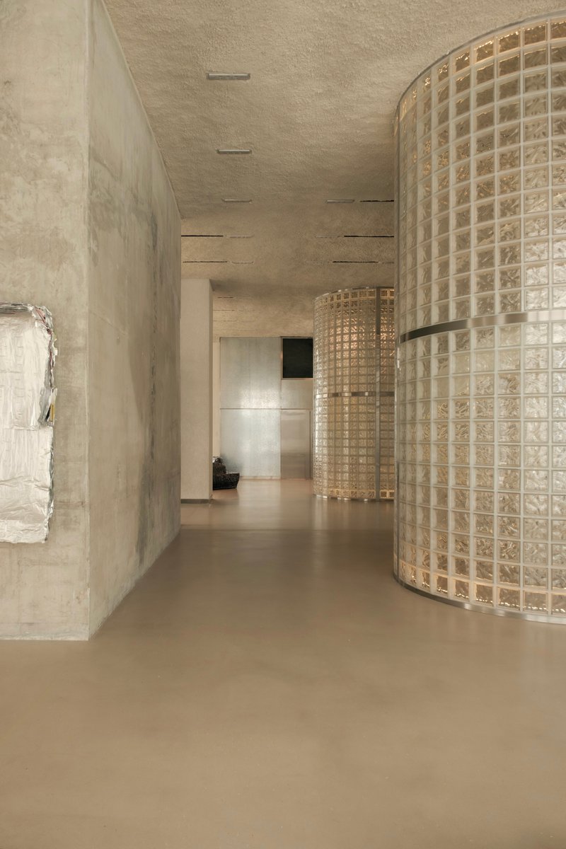 Corridor with cast concrete walls and curved glass block screen under linear ceiling slots