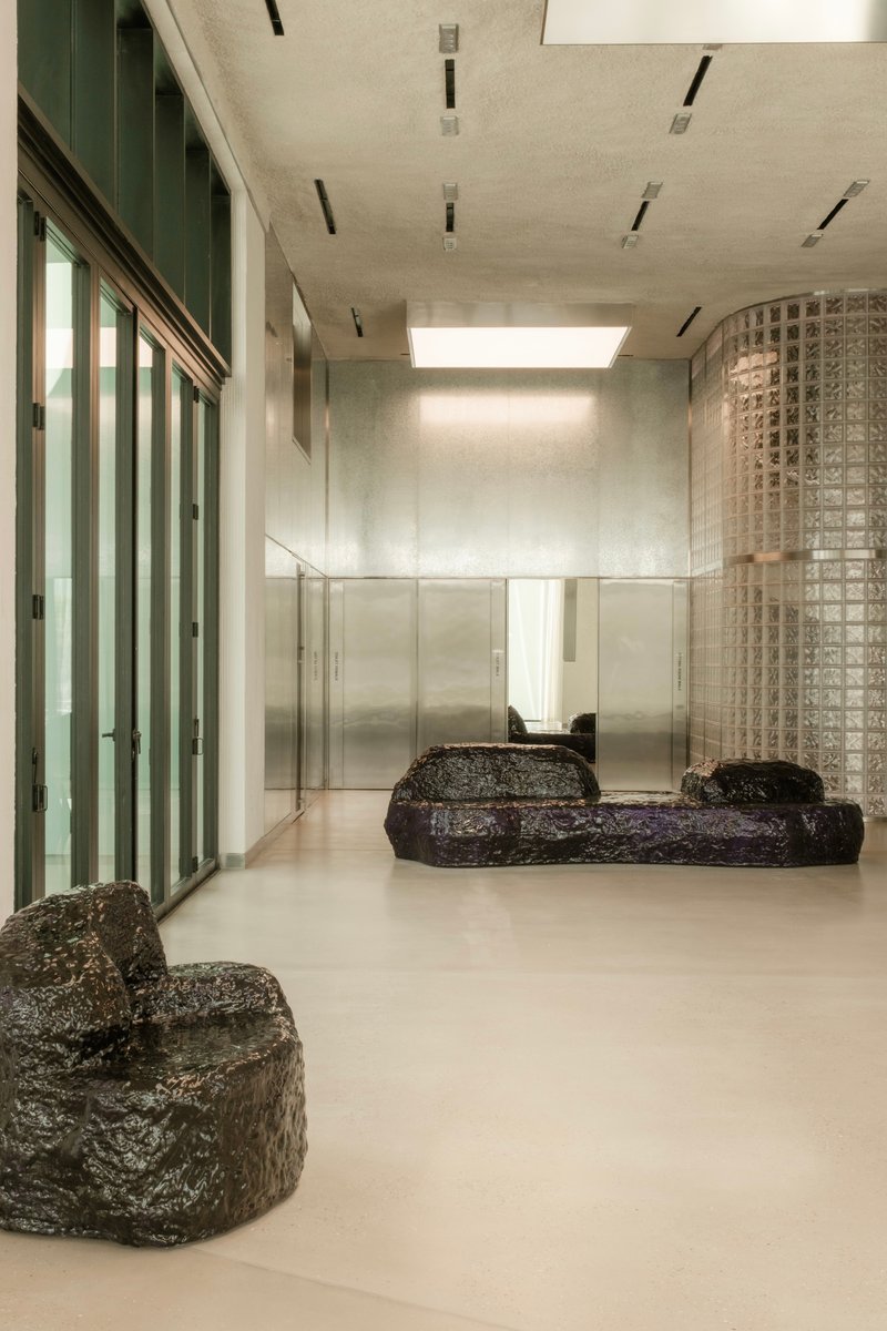 Interior lobby with polished concrete floor, dark stone seating, glass block partition and skylight above