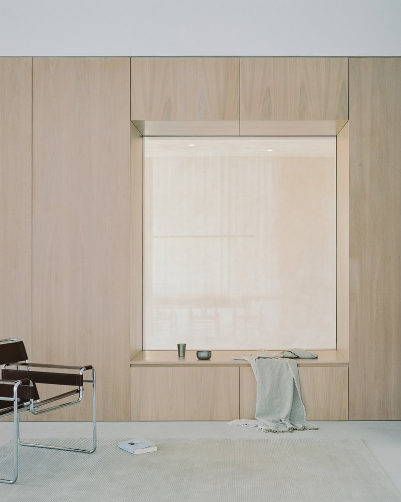 Timber-framed window alcove with built-in bench and sheer white roller shade in pale interior