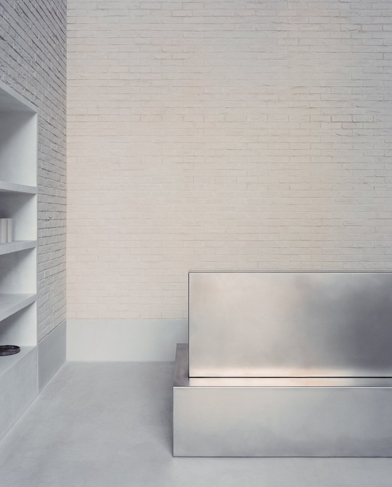 Detail of stainless steel stair treads with integrated lighting against a white painted brick wall