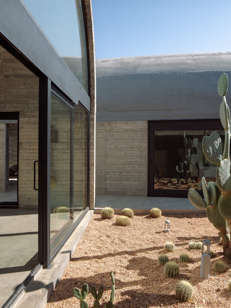 Interior courtyard with gravel bed, barrel cactus, prickly pear, and board-formed concrete walls under open sky