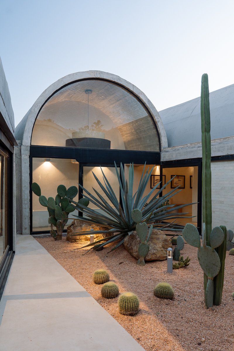 Arched concrete vault framing the courtyard garden with agave, saguaro, and prickly pear at twilight
