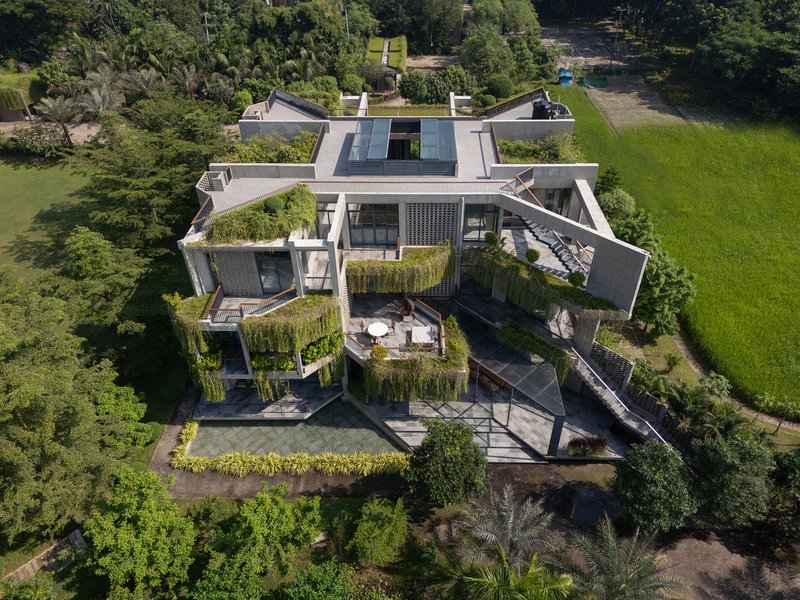 Aerial view of the multi-level residence with planted terraces and green roofs surrounded by trees and lawn
