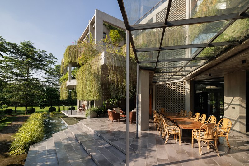 Outdoor terrace with glass canopy and reflecting pool beside planters with cascading greenery