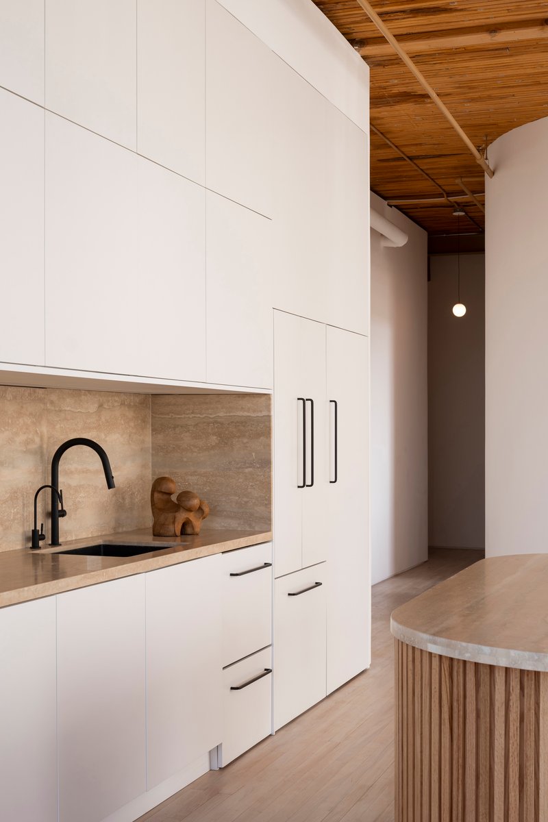 Galley kitchen with white cabinets, travertine backsplash and timber coffered ceiling above