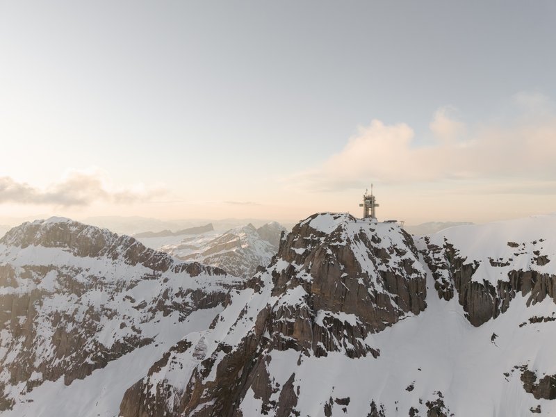 Observation structure with white mast perched atop a rocky summit at sunrise