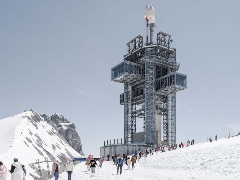 Lattice steel tower with cantilevered platforms and visitors gathered on the snow-covered plaza below