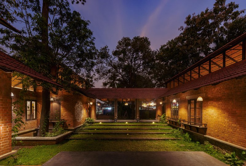 Courtyard view toward the connecting breezeway under a tile roof with large trees silhouetted against an evening sky