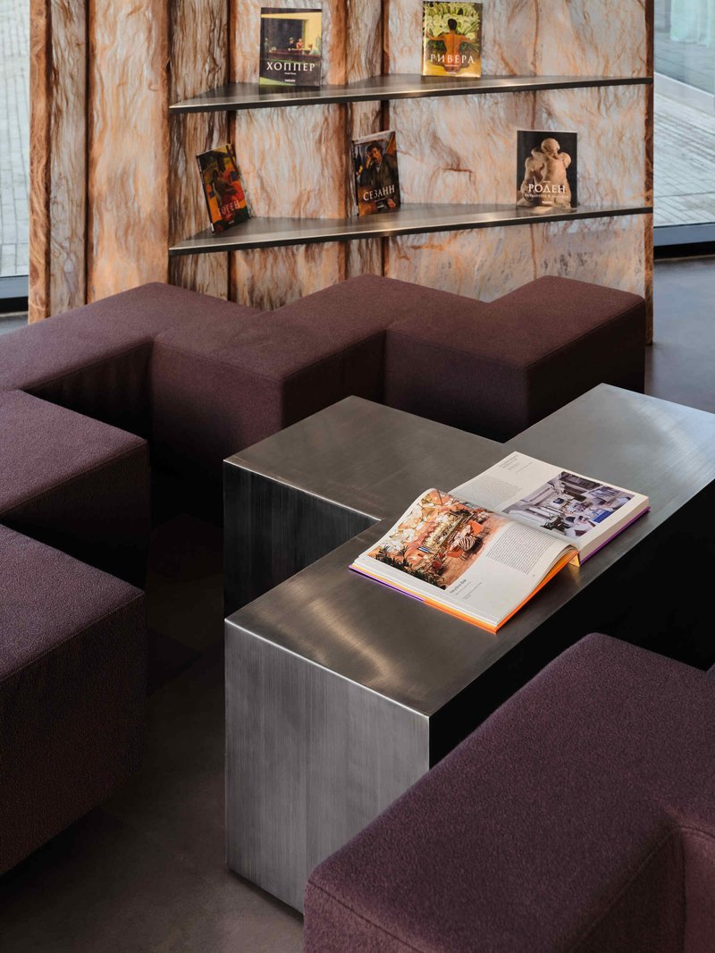Close-up of metal cube side tables with burgundy upholstered seating against a veined copper wall panel