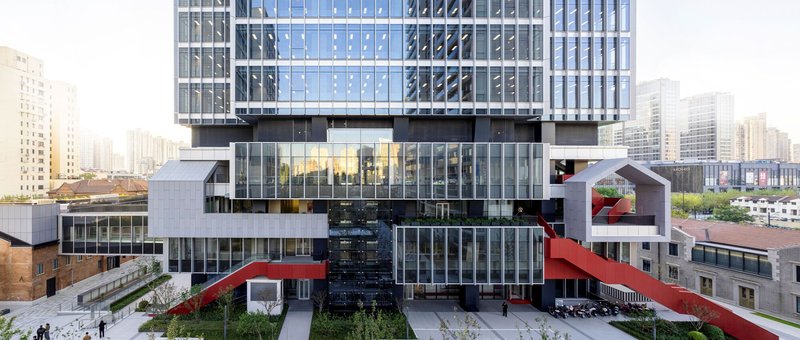 Courtyard view of the stacked glass and white panel volumes with red pedestrian bridges and planted beds