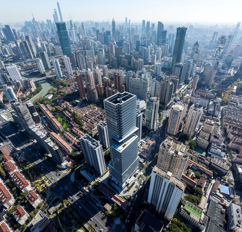Aerial view of the tower complex among dense high-rise urban fabric in hazy daylight