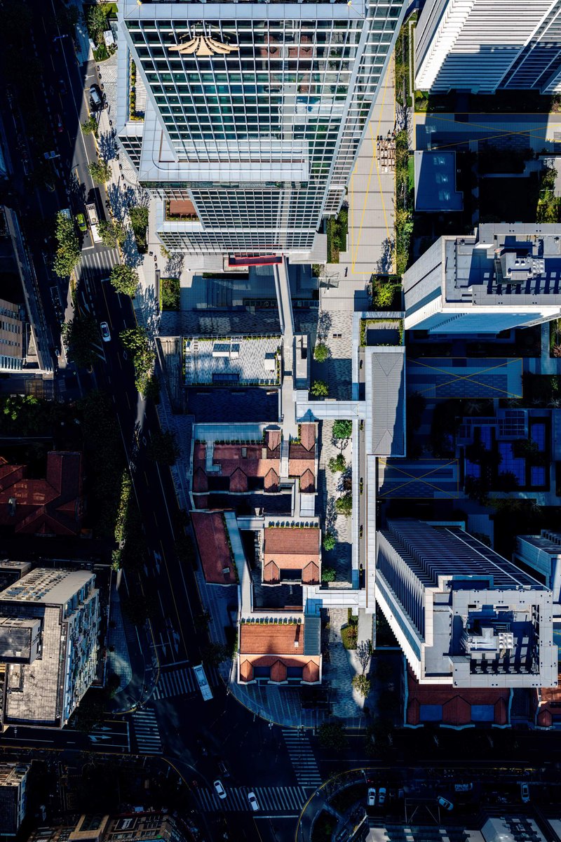 Drone view of the striped glass tower rising among restored heritage rooftops and tree-lined streets