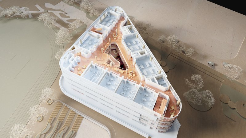 Aerial view of a physical model showing a triangular building with a central courtyard and surrounding landscape