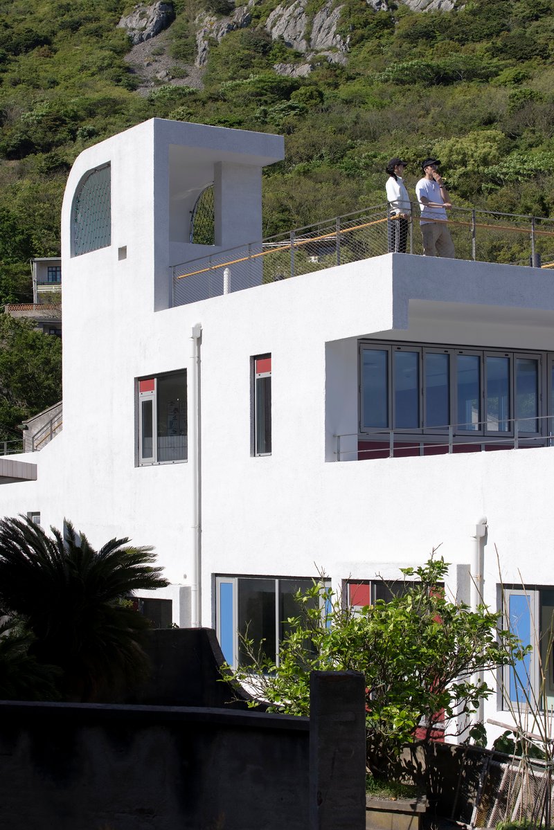 White rooftop terrace with curved tower element and two figures standing by the mesh railing