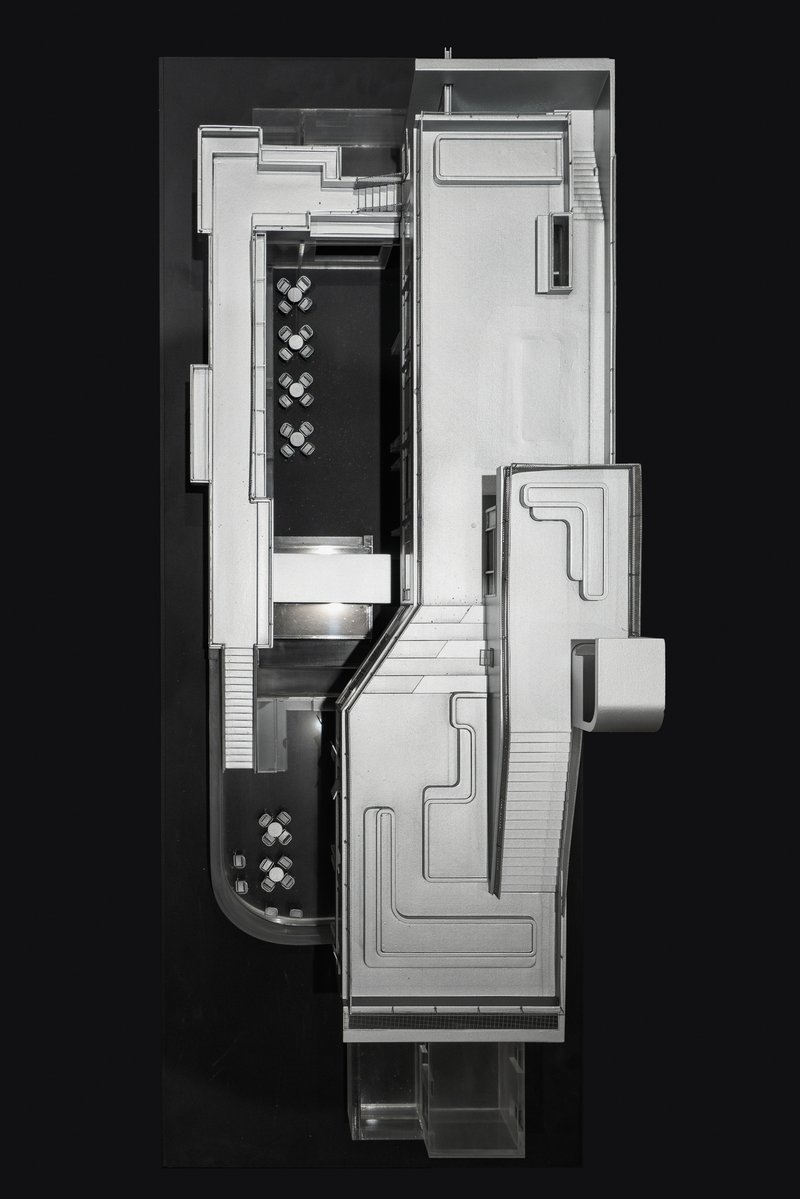 Top-down physical model view showing split-level interior spaces with two dining areas and stairs