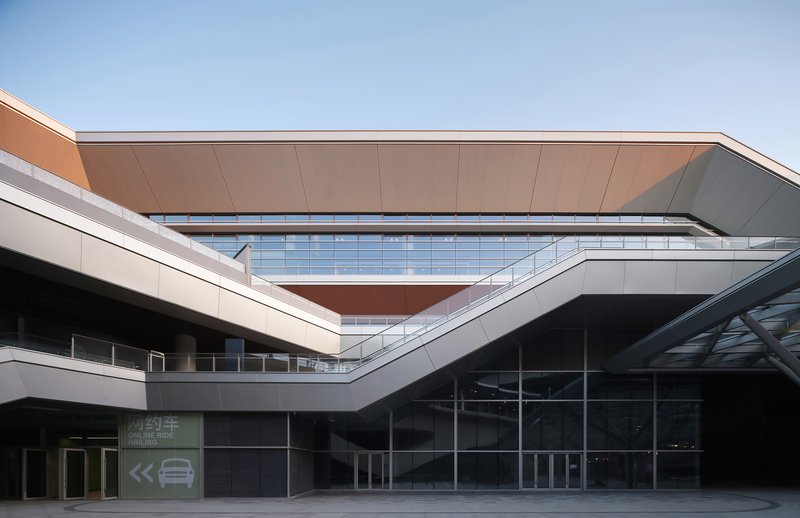 Courtyard view showing layered facades with copper-clad canopy and gridded glass curtain wall