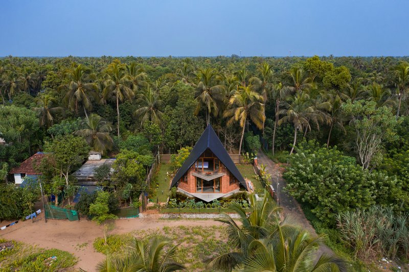 Aerial view of the A-frame structure surrounded by dense palm canopy and garden