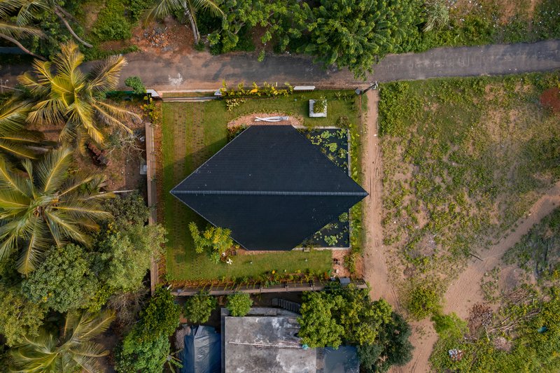 Aerial view of the pyramidal roof nestled among coconut palms and grassy fields